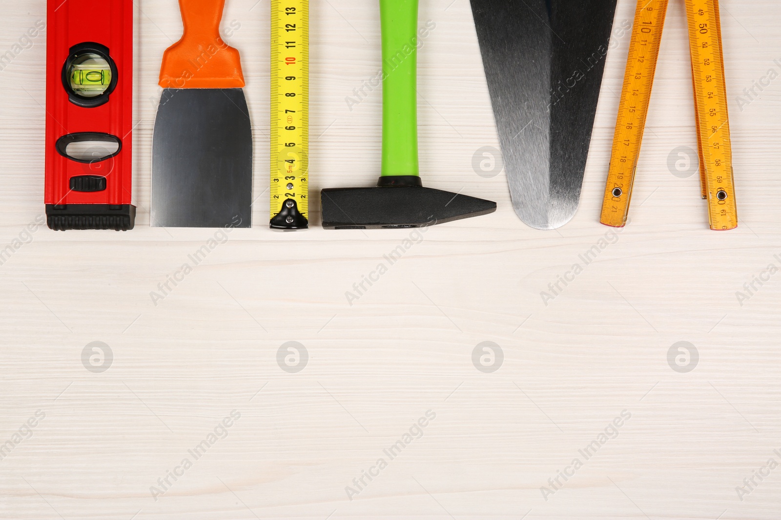 Photo of Different construction tools on light wooden table, flat lay. Space for text