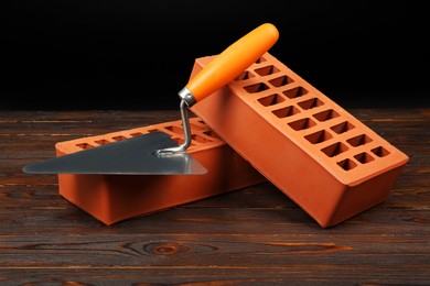 Red bricks and putty knife on wooden table. Building material