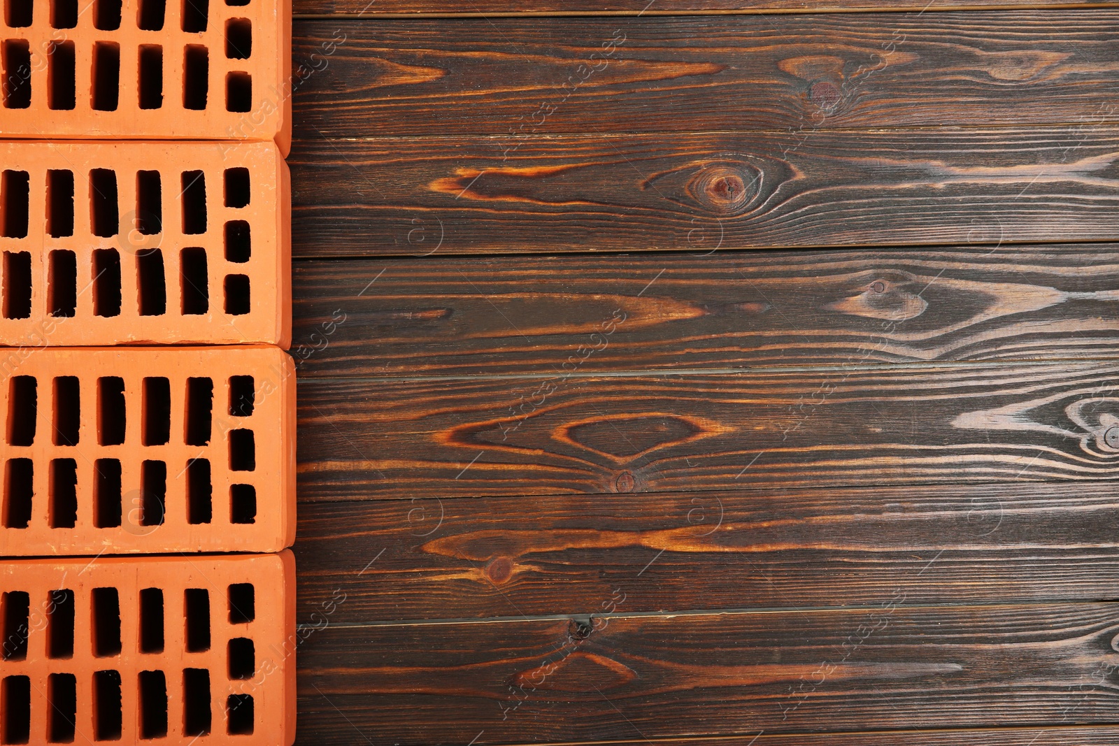 Photo of Many red bricks on wooden table, flat lay with space for text. Building material