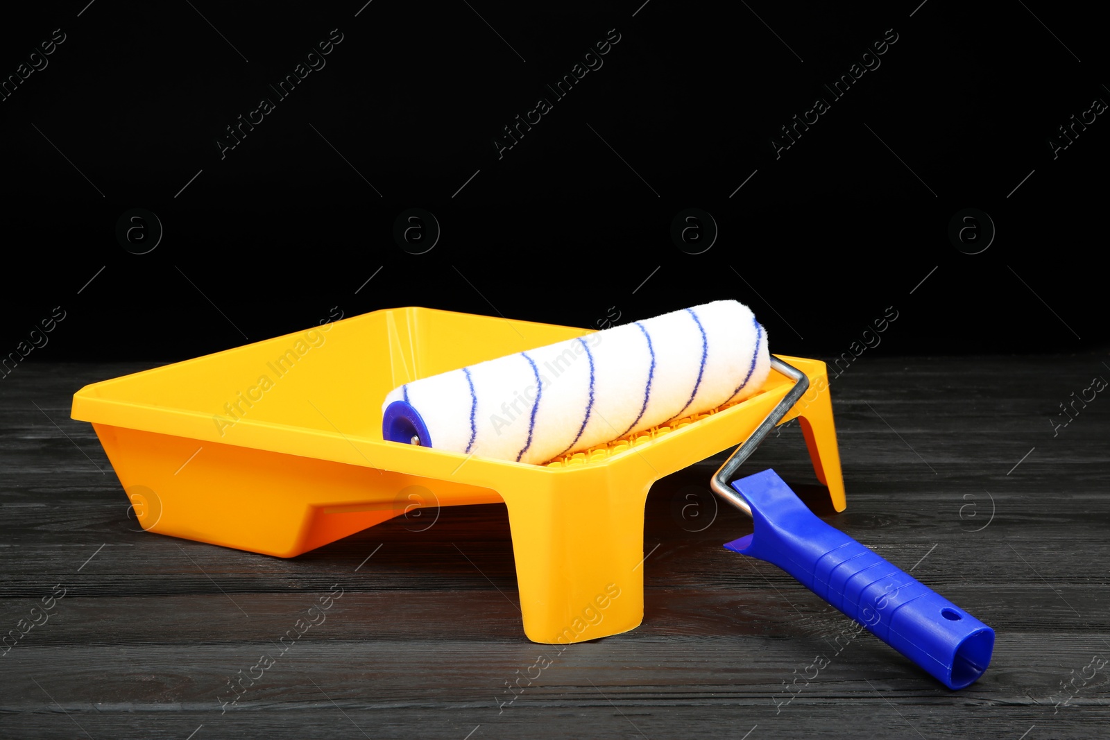 Photo of Tray and paint roller on dark wooden table