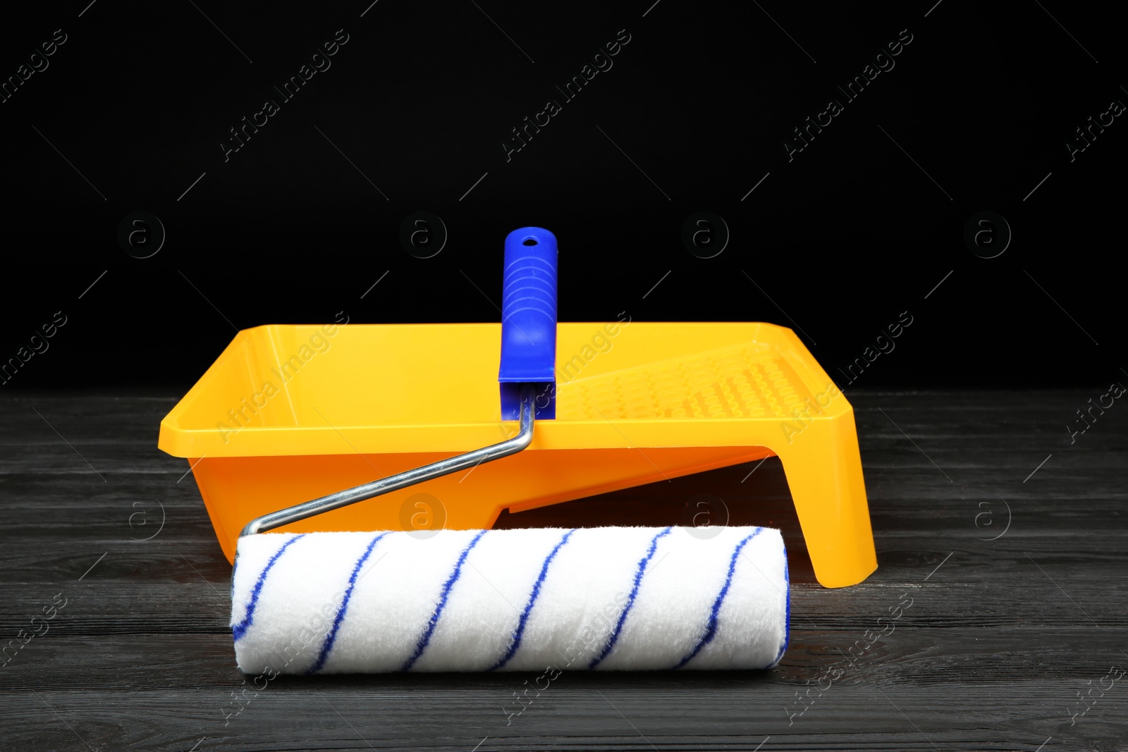 Photo of Tray and paint roller on dark wooden table