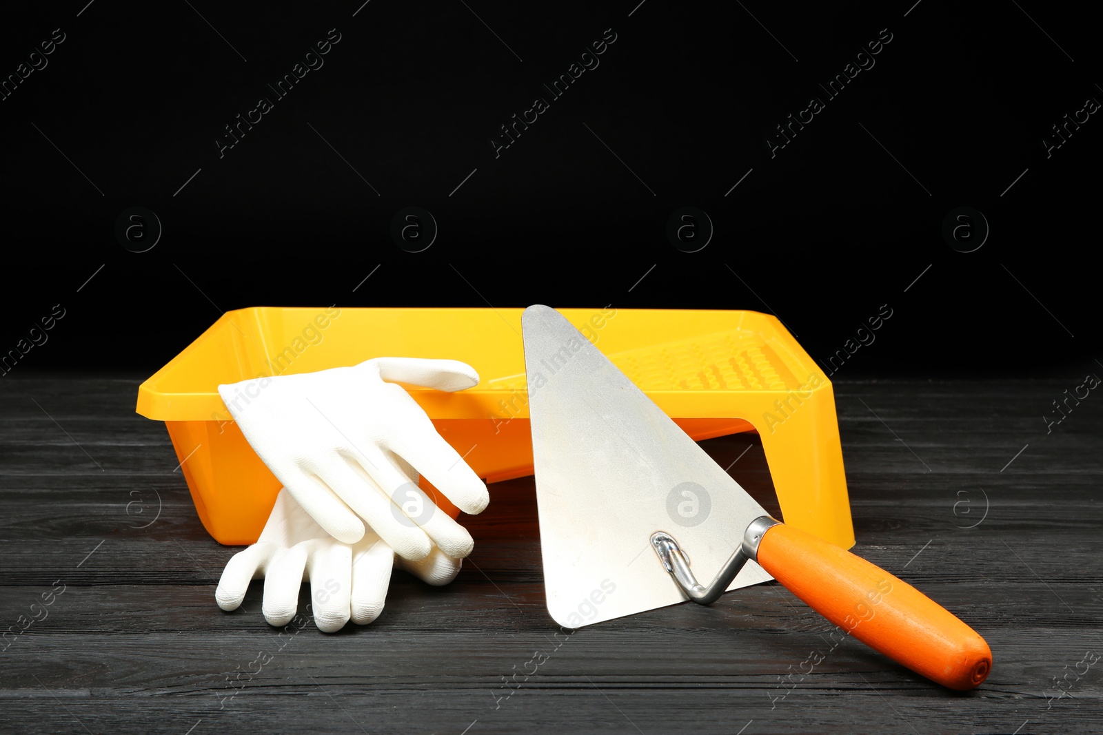 Photo of Tray, putty knife and rubber gloves on dark wooden table