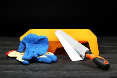 Photo of Tray, putty knife and rubber gloves on dark wooden table