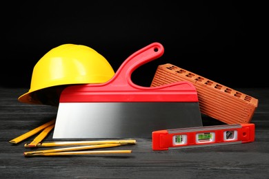 Different construction tools and yellow hard hat on dark wooden table