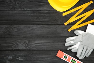 Photo of Different construction tools and safety equipment on dark wooden table, flat lay. Space for text