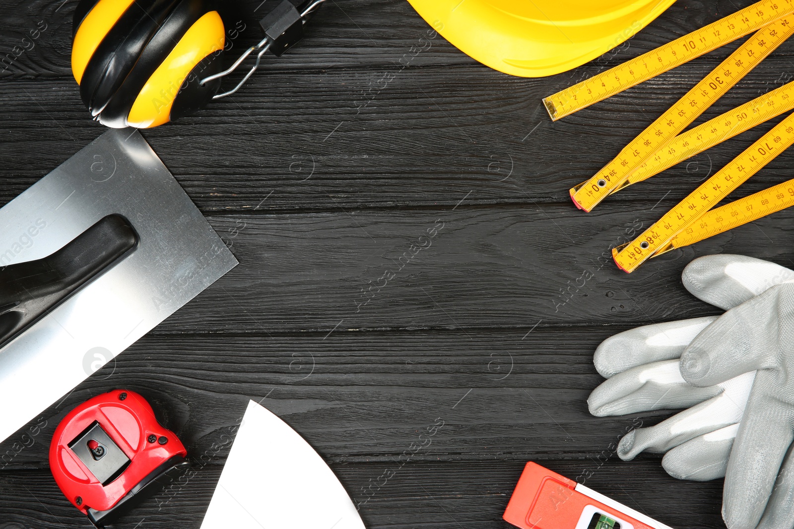 Photo of Different construction tools and safety equipment on dark wooden table, flat lay. Space for text