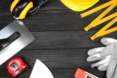 Photo of Different construction tools and safety equipment on dark wooden table, flat lay. Space for text