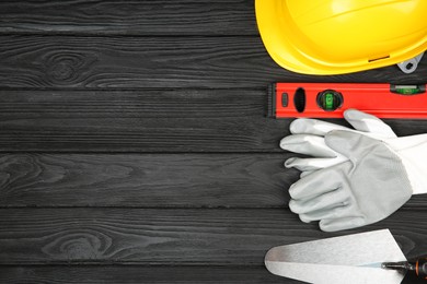 Photo of Different construction tools and safety equipment on dark wooden table, flat lay. Space for text