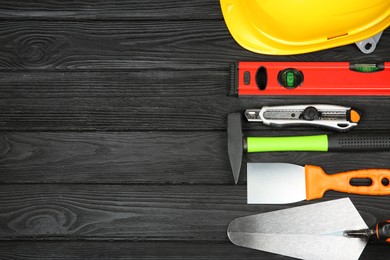 Photo of Different construction tools and safety equipment on dark wooden table, flat lay. Space for text