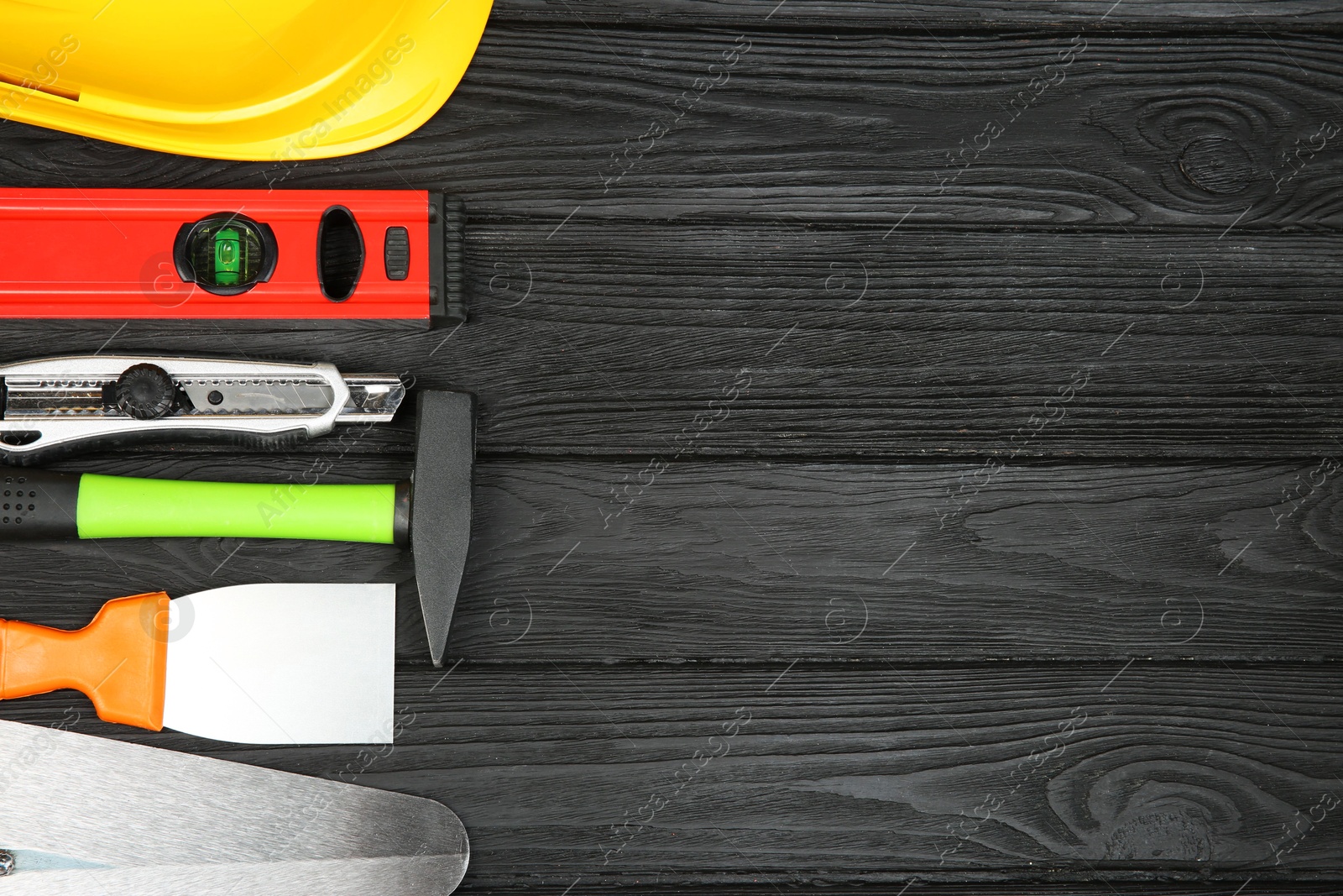 Photo of Different construction tools and yellow hard hat on dark wooden table, above view