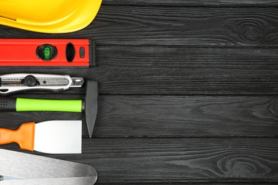 Photo of Different construction tools and yellow hard hat on dark wooden table, above view