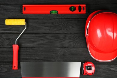 Photo of Different construction tools and red hard hat on dark wooden table, flat lay. Space for text