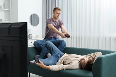 Photo of Young brothers playing video game on sofa at home