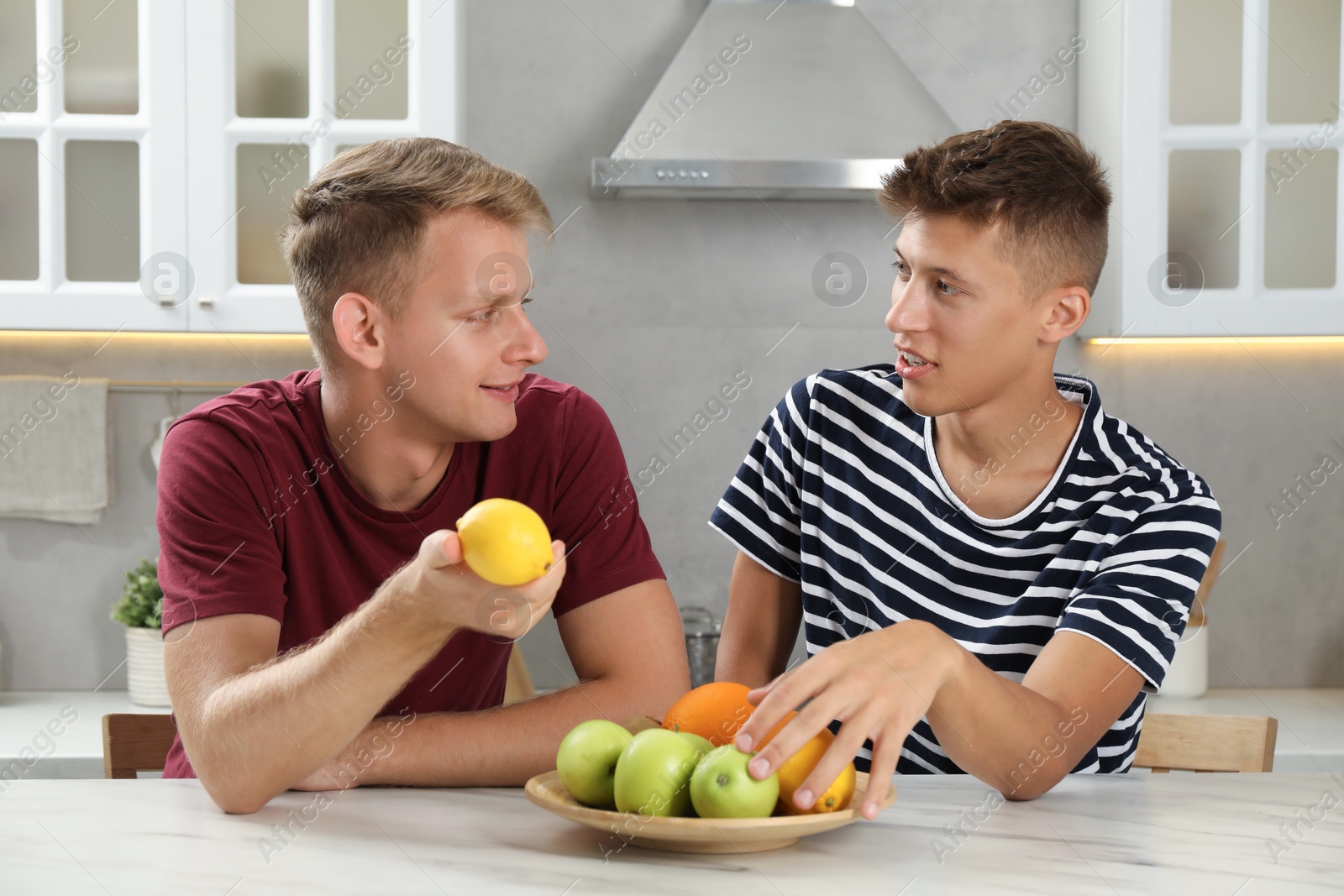 Photo of Young brothers spending time together in kitchen