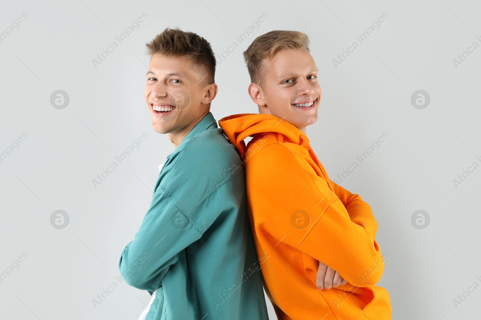 Photo of Portrait of two happy brothers posing with crossed arms on light background