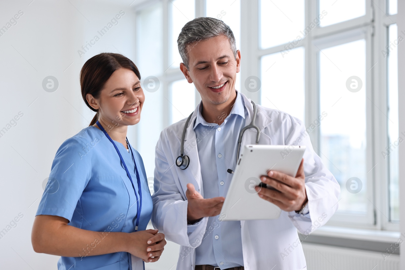 Photo of Smiling healthcare workers with tablet in hospital