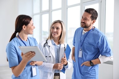 Group of healthcare workers with tablet talking in hospital