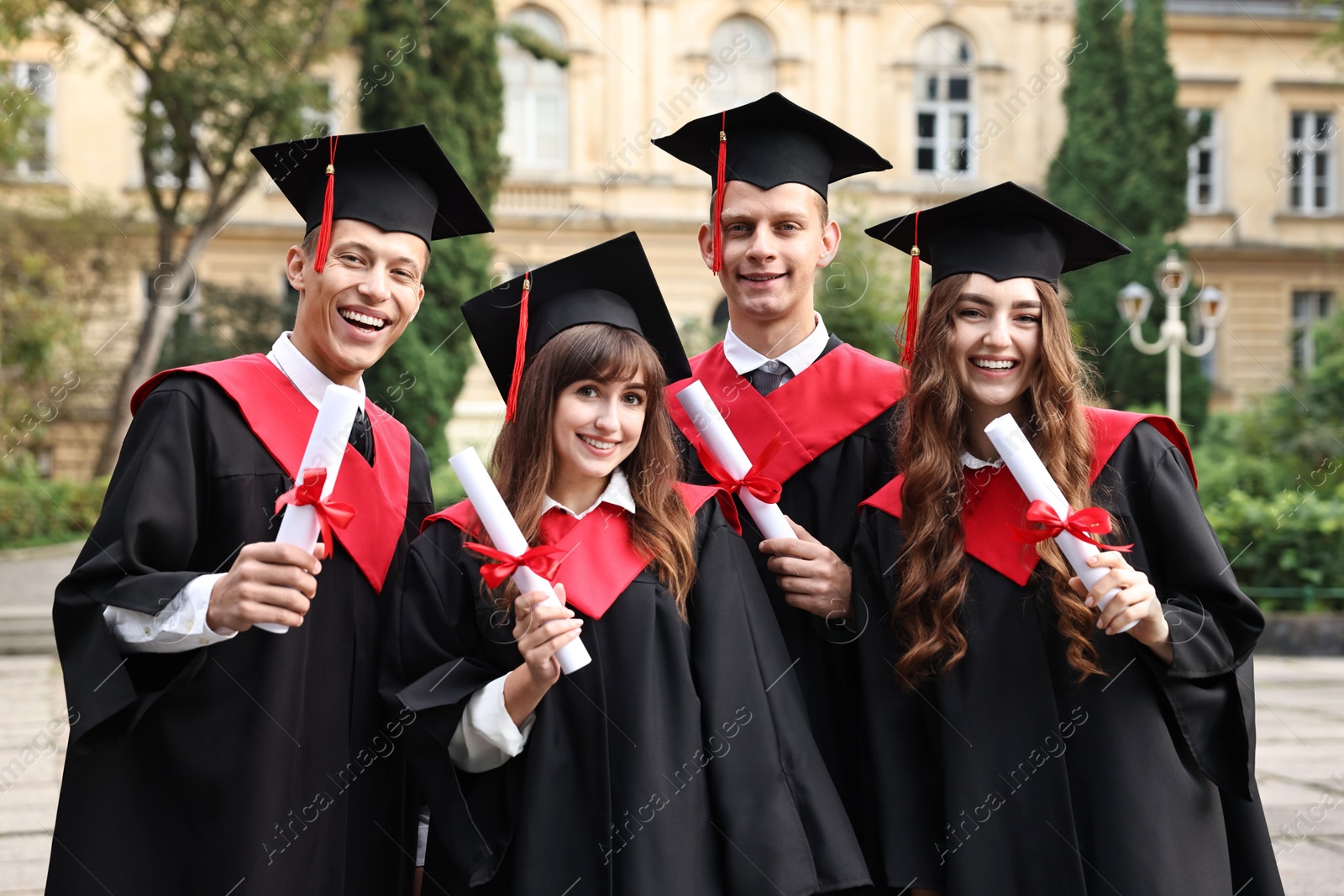 Photo of Happy students with diplomas after graduation ceremony outdoors