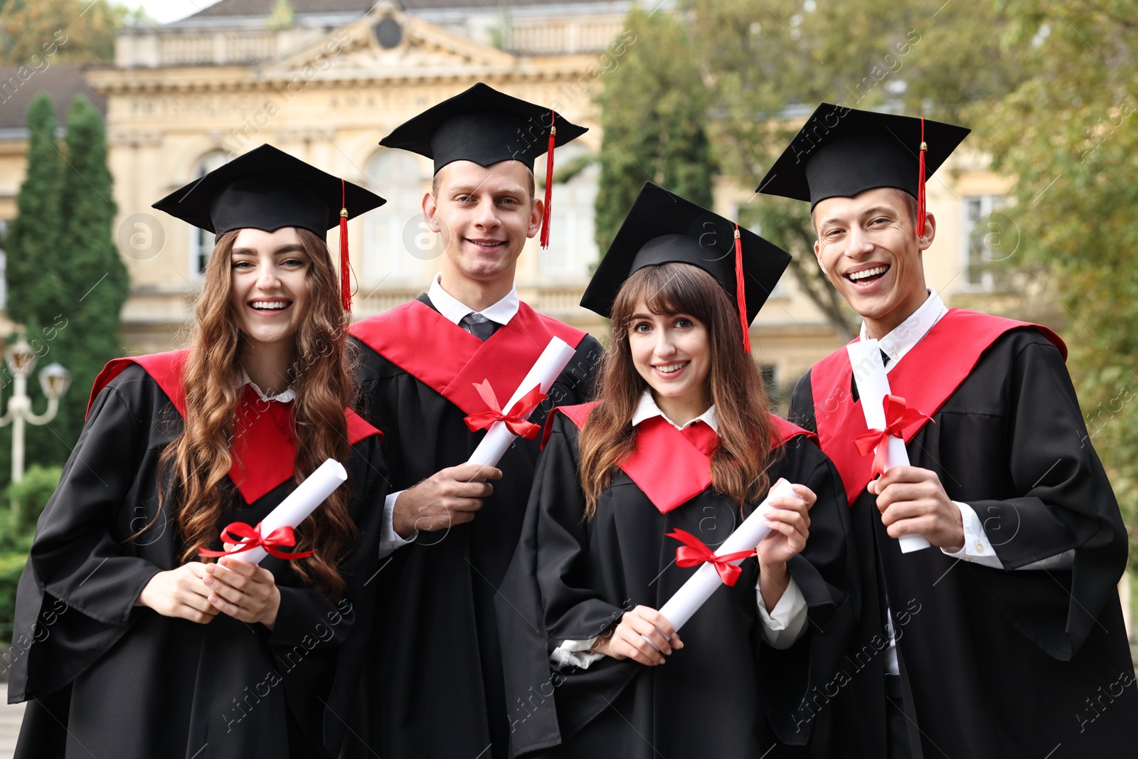 Photo of Happy students with diplomas after graduation ceremony outdoors