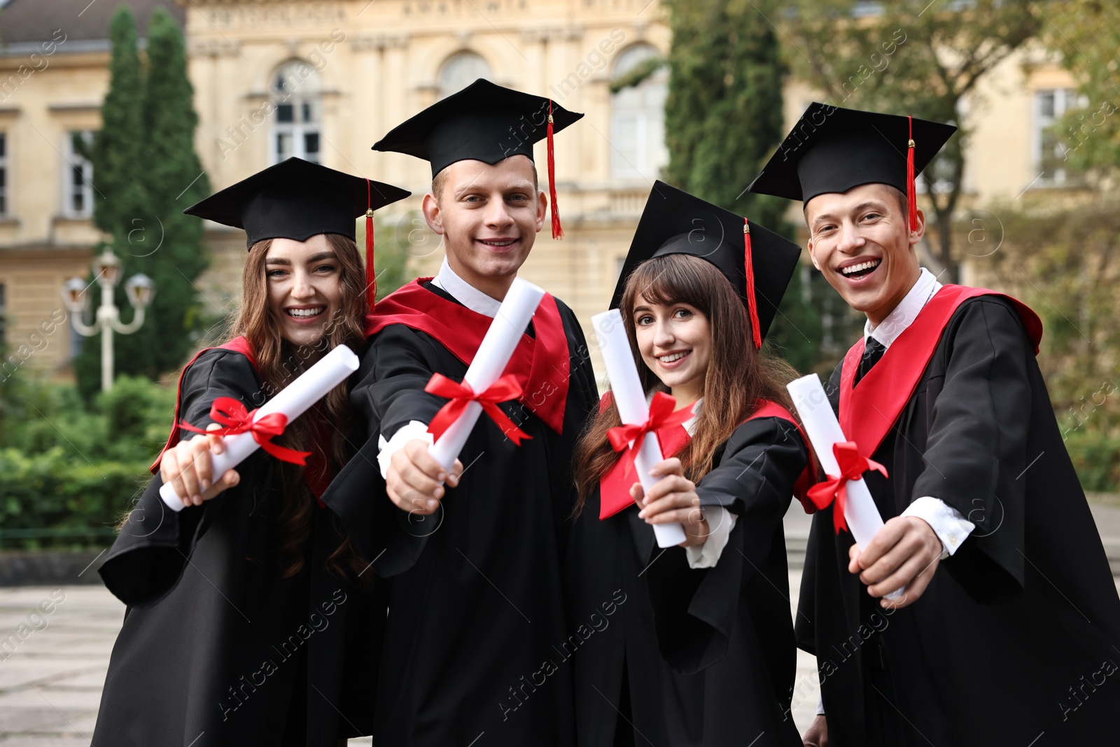 Photo of Happy students with diplomas after graduation ceremony outdoors