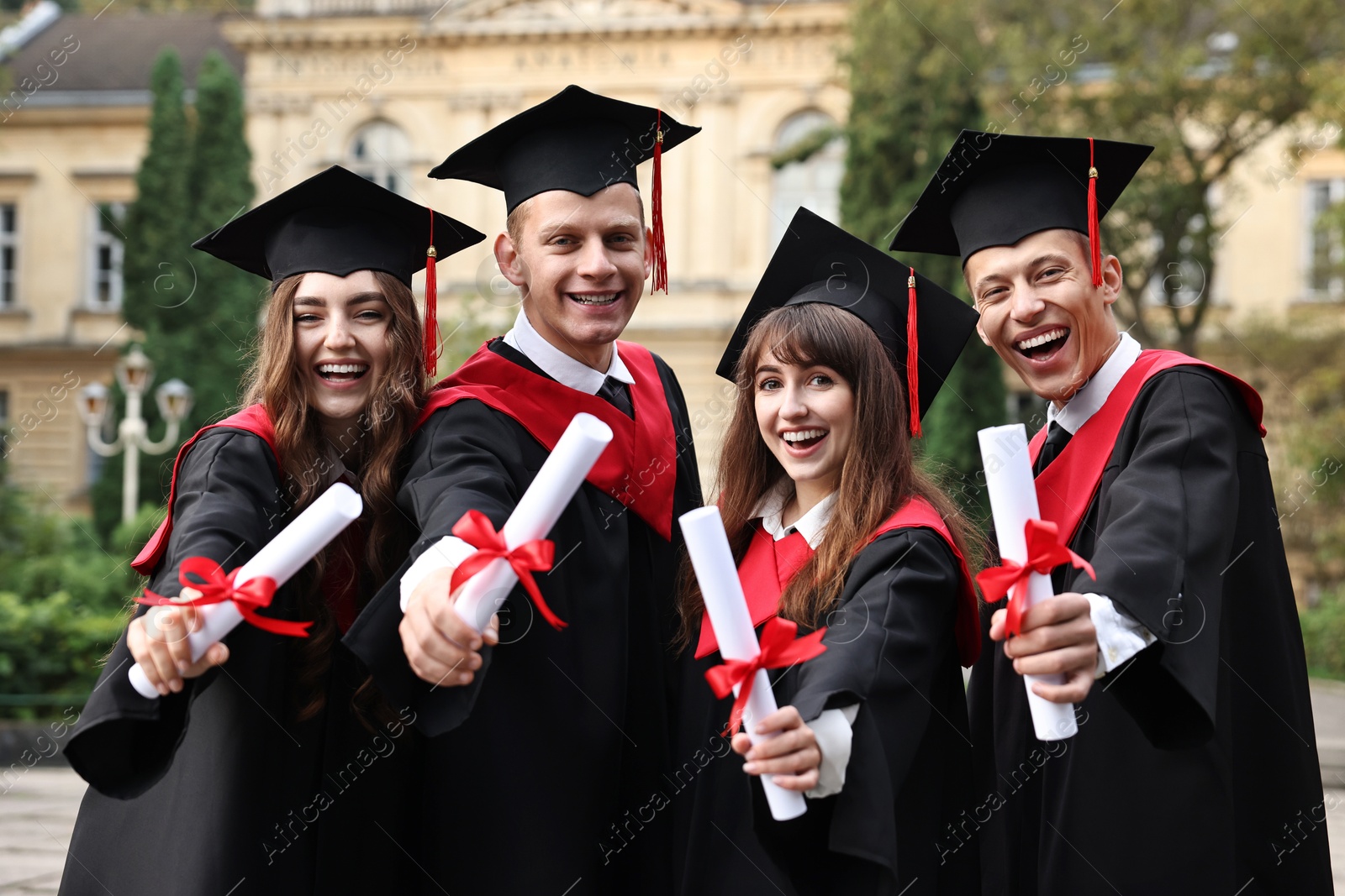 Photo of Happy students with diplomas after graduation ceremony outdoors