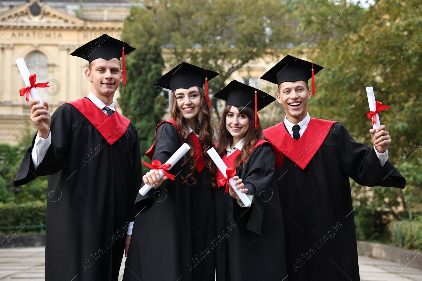 Photo of Happy students with diplomas after graduation ceremony outdoors