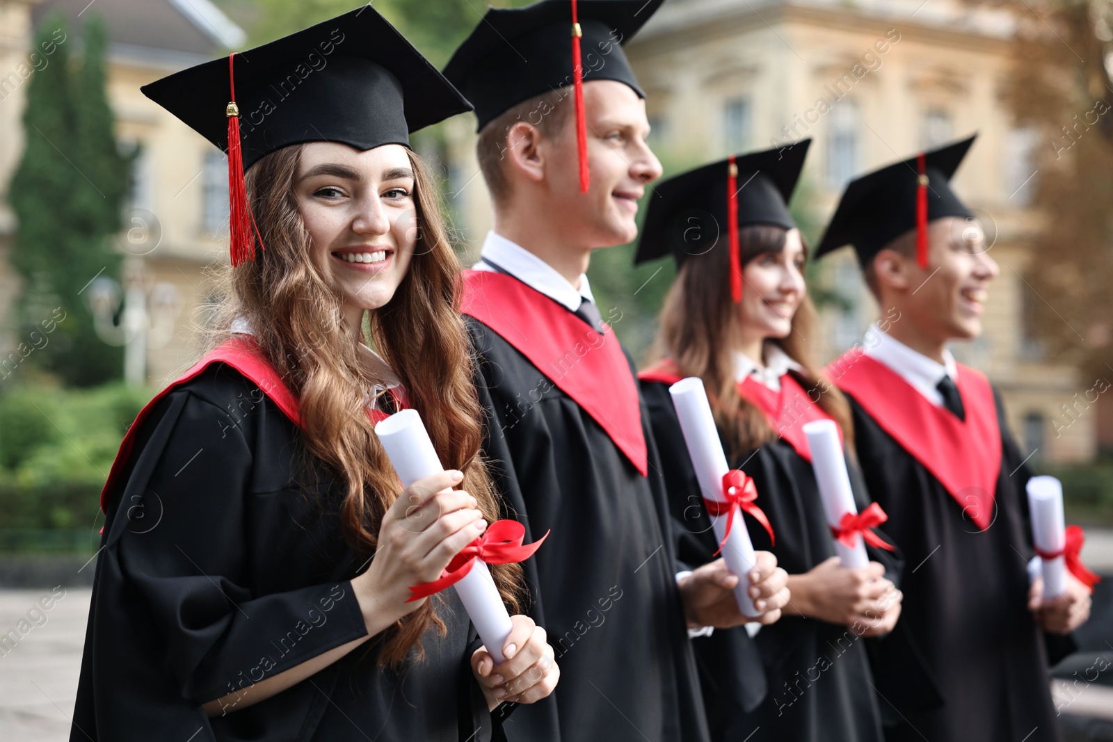 Photo of Happy students with diplomas after graduation ceremony outdoors, selective focus