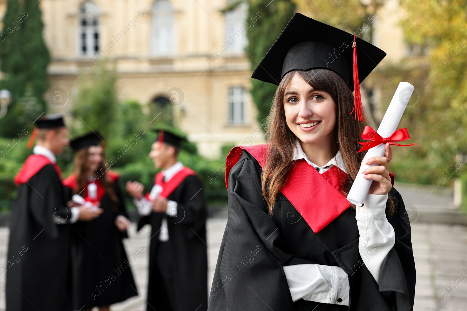 Photo of Happy students with diplomas after graduation ceremony outdoors, selective focus