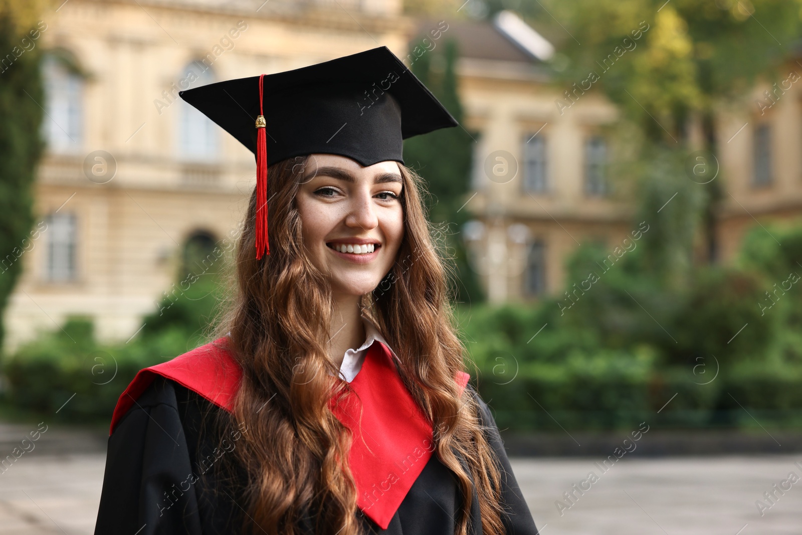 Photo of Graduation ceremony. Happy student in academic dress outdoors