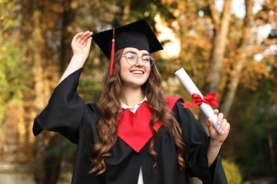 Happy student with diploma after graduation ceremony outdoors