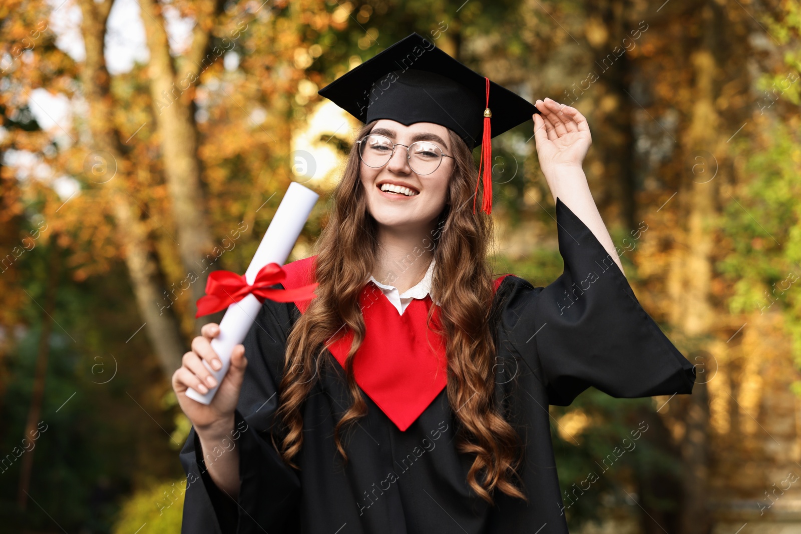 Photo of Happy student with diploma after graduation ceremony outdoors