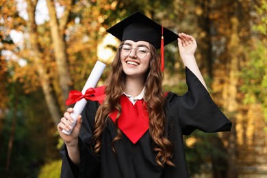 Happy student with diploma after graduation ceremony outdoors