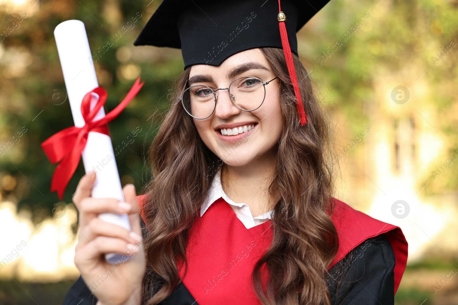 Photo of Happy student with diploma after graduation ceremony outdoors