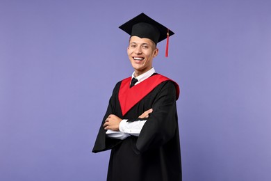 Photo of Happy student with crossed arms after graduation on violet background