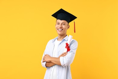 Photo of Happy student with diploma after graduation on orange background