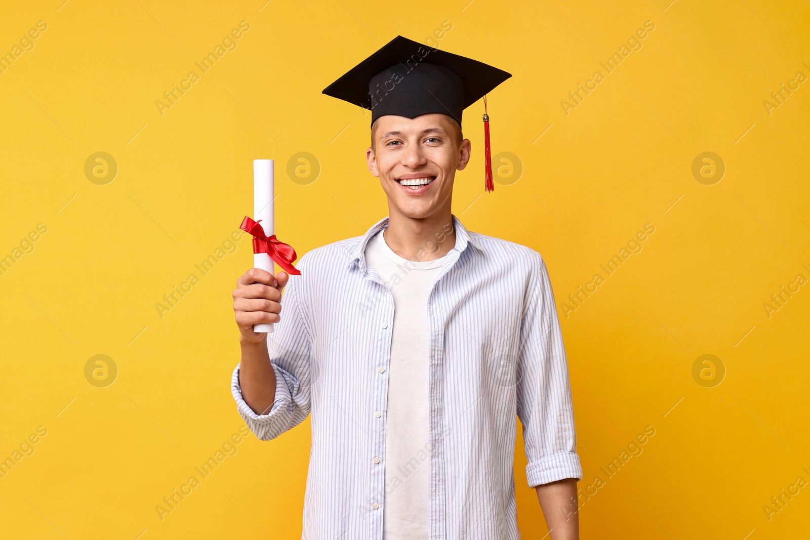 Photo of Happy student with diploma after graduation on orange background