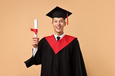 Photo of Happy student with diploma after graduation on beige background