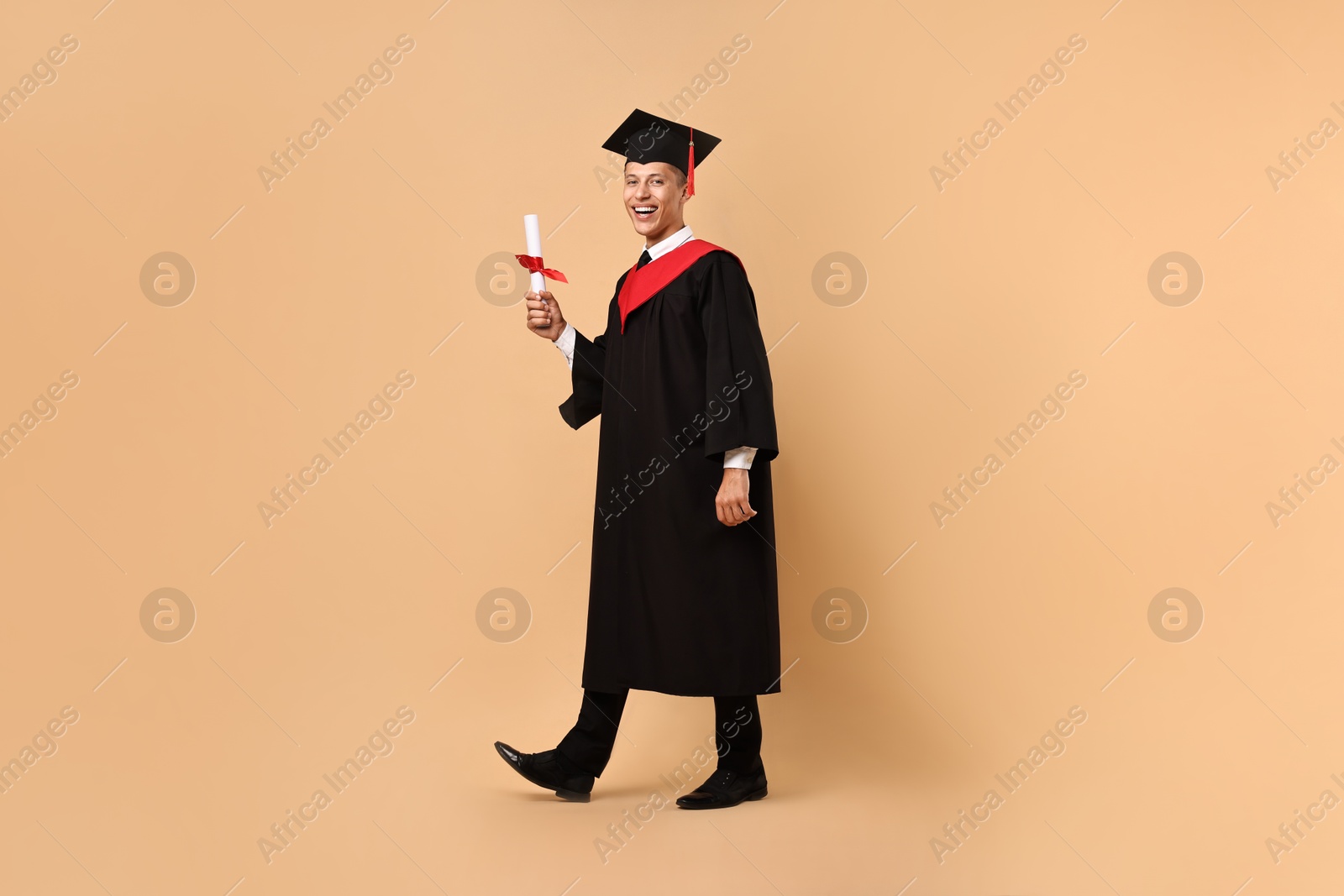 Photo of Happy student with diploma after graduation on beige background