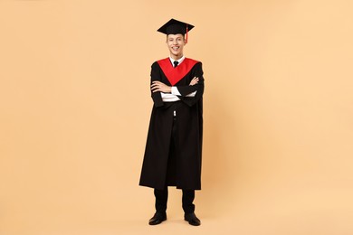 Photo of Happy student with crossed arms after graduation on beige background