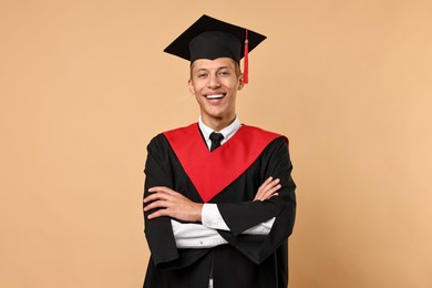 Photo of Happy student with crossed arms after graduation on beige background