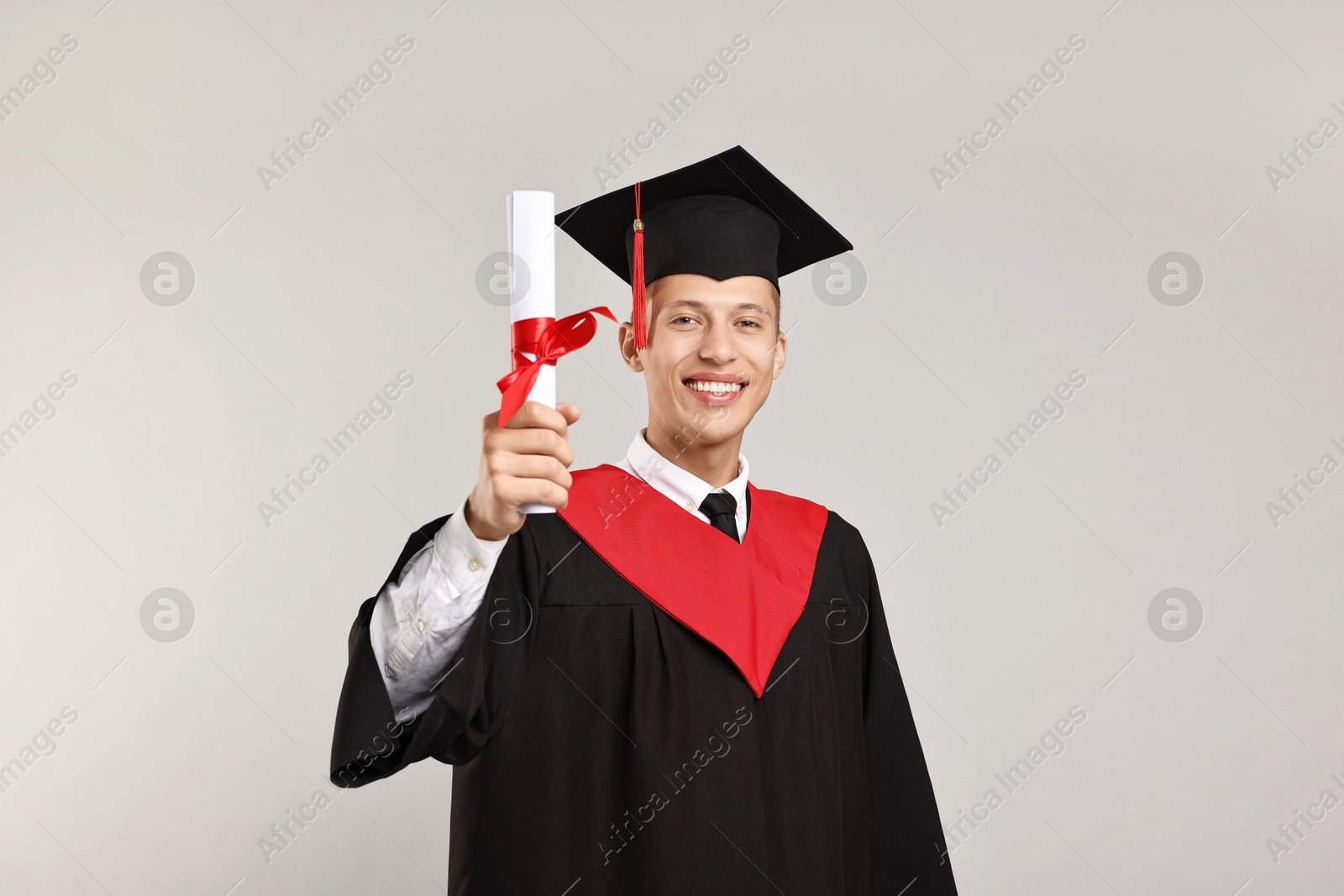 Photo of Happy student with diploma after graduation on grey background