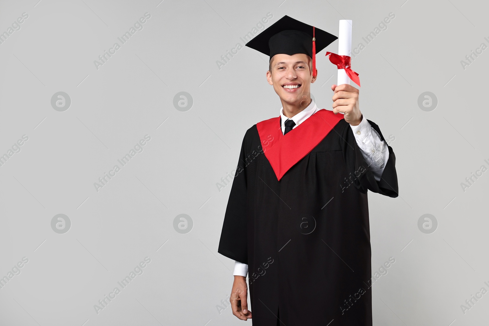 Photo of Happy student with diploma after graduation on grey background. Space for text