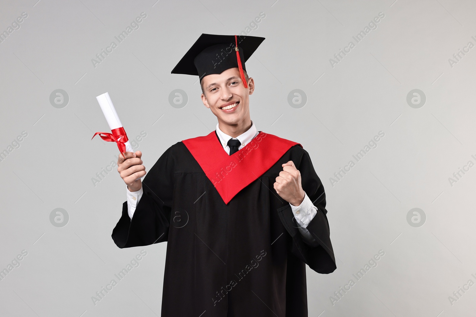 Photo of Happy student with diploma after graduation on grey background