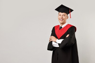 Photo of Happy student with crossed arms after graduation on grey background. Space for text