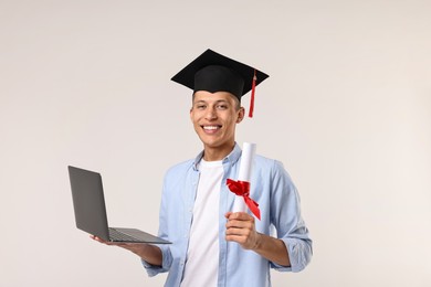 Photo of Happy student with laptop after graduation on light grey background