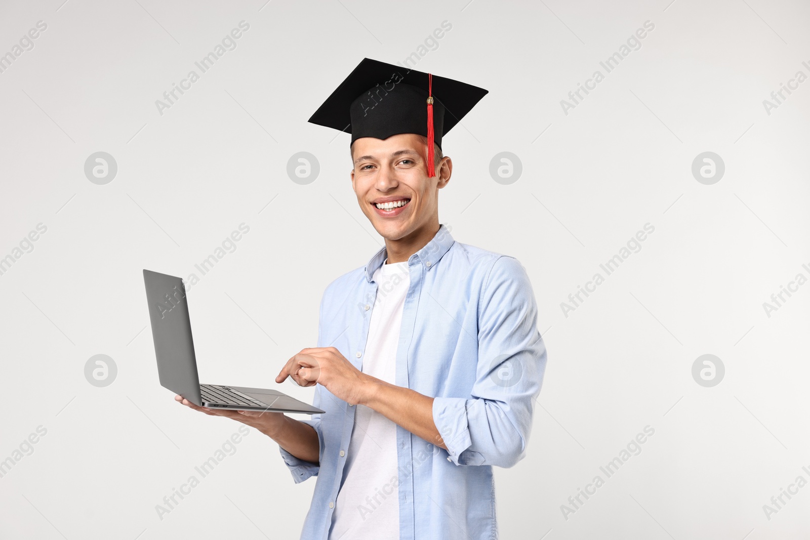 Photo of Happy student with laptop after graduation on light grey background