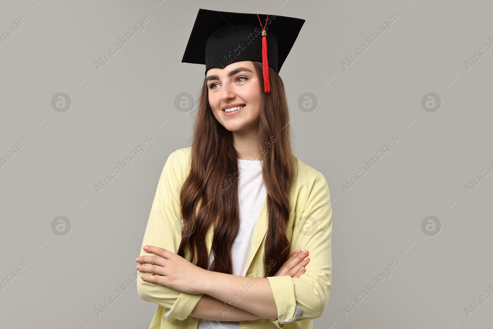 Photo of Happy student with crossed arms after graduation on grey background