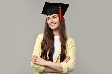 Photo of Happy student with crossed arms after graduation on grey background