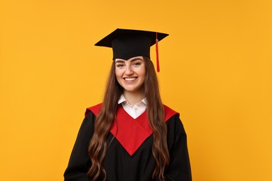 Photo of Happy student after graduation on orange background