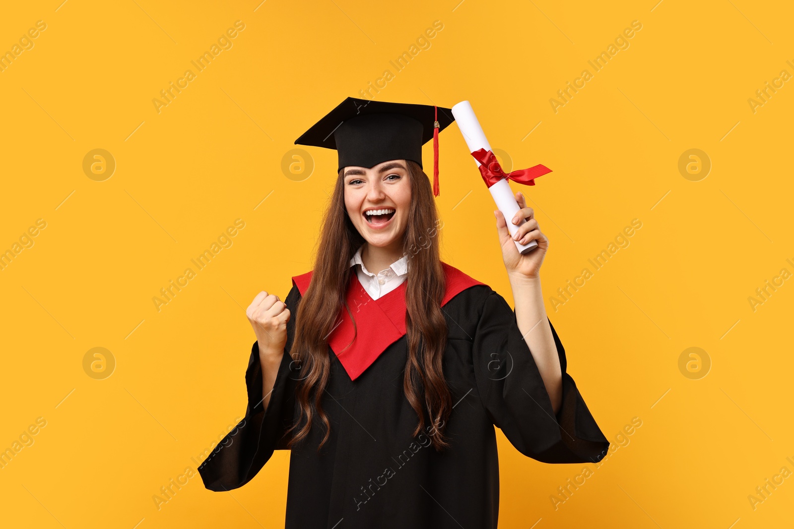 Photo of Happy student with diploma after graduation on orange background